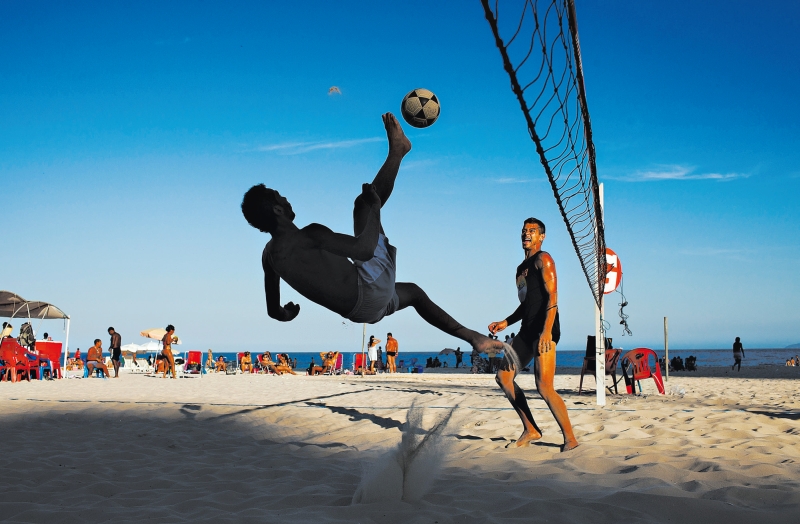 Um jogador no Rio de Janeiro corta com o pé numa partida de futevôlei, onde não se pode usar as mãos para mandar a bola por sobre a rede | Lalo de Almeida /The New York Times