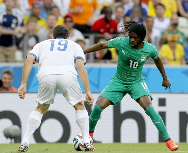 O grego Socratis Papastathopoulos (esq.) enfrenta Gervinho, da Costa do Marfim, em partida do Grupo C | 