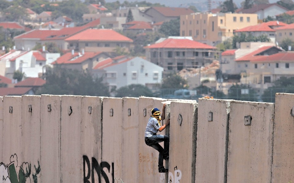 Israelenses e palestinos se tornaram virtualmente estranhos. Palestino escala barreira | abbas momani/aFP  getty images