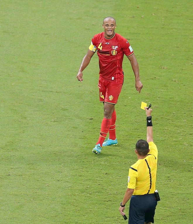 O jogador da Bélgica Vincent Kompany recebe cartão amarelo do árbitro Djamel Haimoudi |