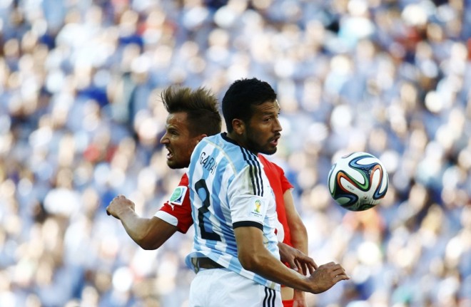 Haris Seferovic da Suíça e o argentino Ezequiel Garay pulam para cabecear |