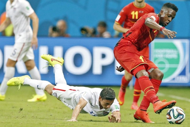 Alejandro Bedoya cai durante disputa de bola com o jogador da Bélgica Divock Origi |