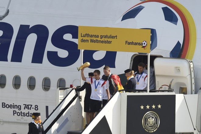 Capitão Phillip Lahm carrega a taça ao descer do avião, no Aeroporto de Tegel |