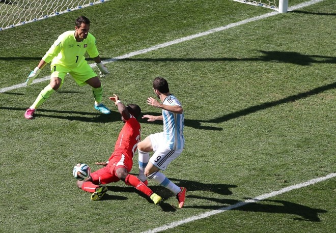 O atacante argentino Gonzalo Higuaín tenta passar pelo zagueiro Johan Djourou e marcar no goleiro suíço Diego Benaglio |
