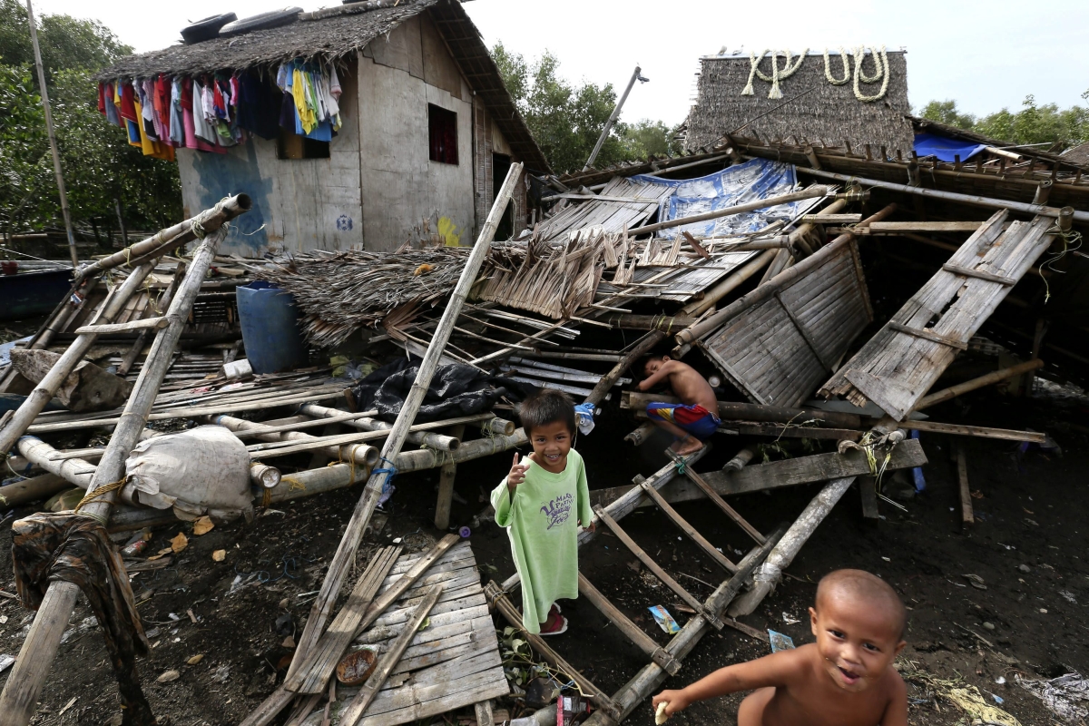 Crianças brincam em meio aos destroços de uma casa afetada pelo tufão Rammasun em Batangas, ao sul de Manila | EFE/Dennis M. Sabangan