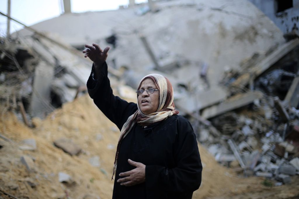 Mulher palestina à frente de casas destruídas por bombas lançadas por Israel, em Gaza | REUTERS/Ibraheem Abu Mustafa