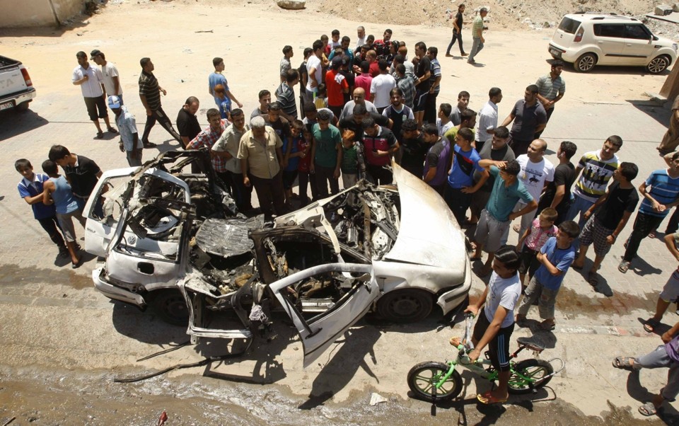 Palestinos se reúnem ao redor de um carro, destruído por um suposto ataque israelense contra a Faixa de Gaza | Reuters/Ahmed Zakot