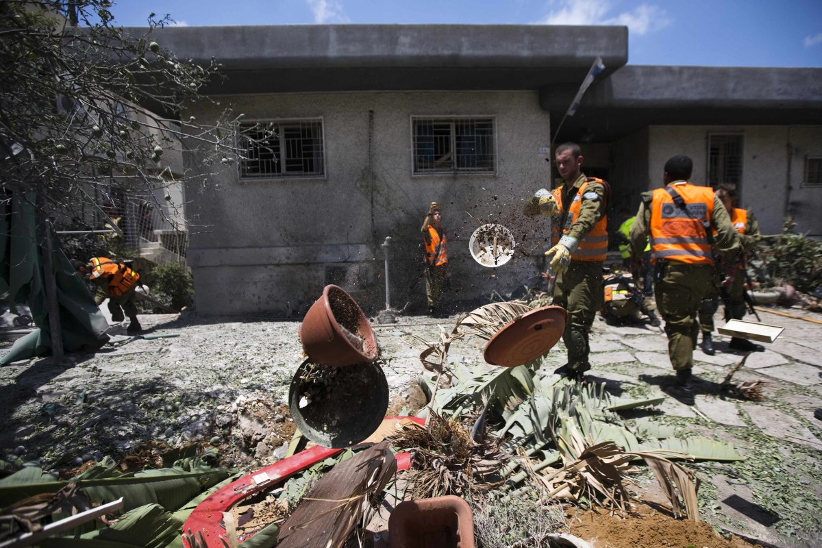 Soldados israelenses limpam destroços após um foguete de militantes palestinos causar danos a uma edificação | Reuters/Amir Cohen