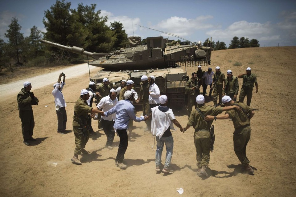 Soldados israelenses se encontram com civis judeus próximo à Gaza. Este domingo marca o sexto dia de uma ofensiva que já matou pelo menos 160 pessoas | Reuters / Amir Cohen