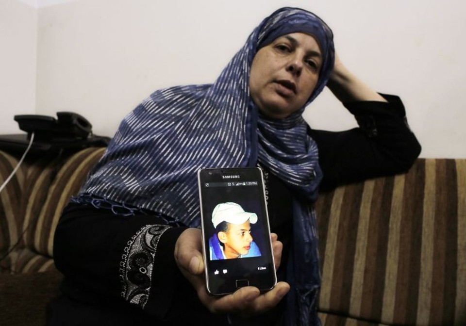 Mãe segura retrato de seu filho, assassinado em possível retaliação | Reuters/ Ammar Awad