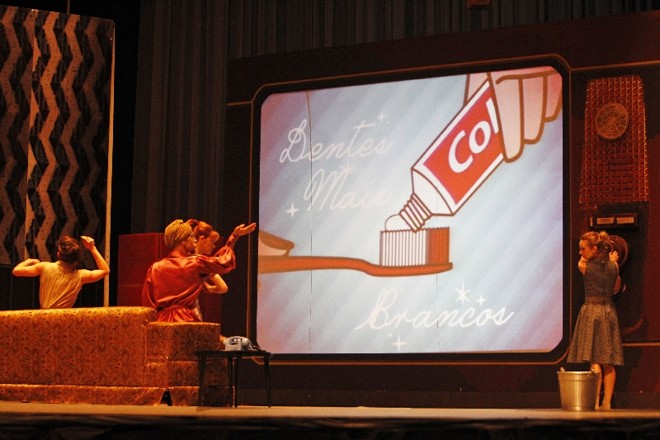 Televisão gigante conduz a trama do balé e apresenta comerciais de época |