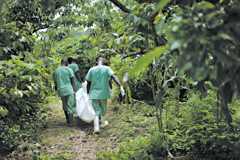 A epidemia de ebola já matou mais de 660 pessoas. Trabalhadores da Cruz Vermelha com o corpo de uma vítima | Samuel Aranda para The New York Times