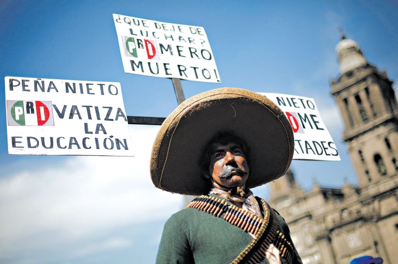 Manifestante mascarado e fantasiado na Cidade do México e cartazes ironizando Peña Nieto e seu partido, o PRI | Reuters