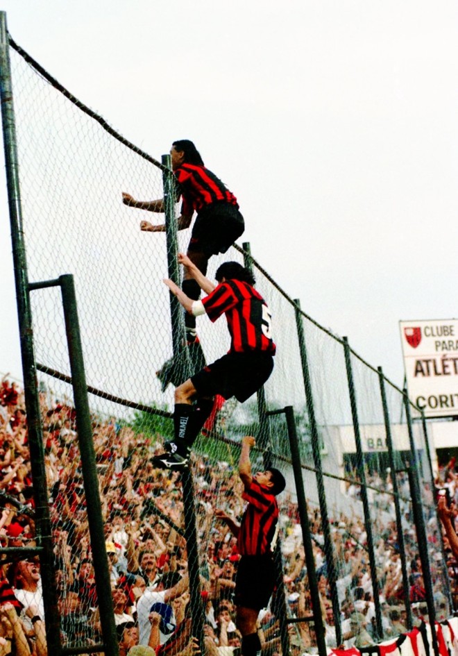 Cena que se tornou clássica da Baixada em sua terceira versão. O atacante Oséas escala o alambrado do gol da entrada após marcar o tento da vitória por 1 a 0 no Atletiba do Brasileiro de 1996 |