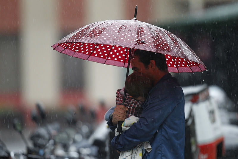 Chuva cai em Curitiba enquanto pai carrega filho no colo no Centro da cidade | Jonathan Campos / Agência de Notícias Gazeta do Povo