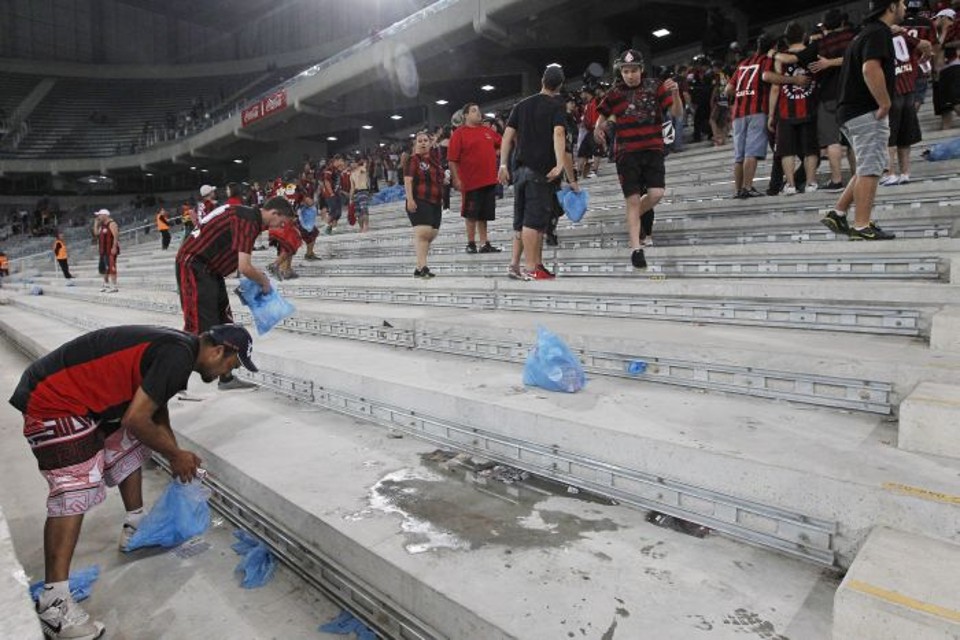 Parte da torcida recolhe lixo na Arena da Baixada após o Atlético vencer o Vitória | Antonio More / Gazeta do Povo