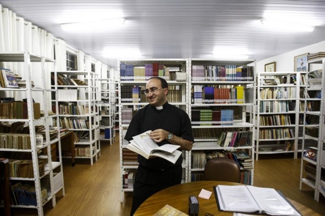 Um dos autores do livro, padre Antônio Luciano folheia o livro na biblioteca do seminário | 