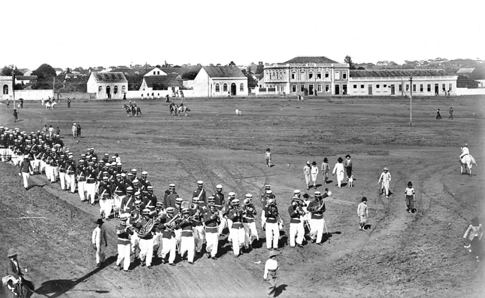 A Praça da Republica em 1906 um descampado usado para manobras militares do quartel que ali estava instalado, o 6º. Regimento de Artilharia, cujo efetivo vemos desfilando. O sobrado ao fundo era o Hospital Militar, mais tarde o prédio foi usado pelo Colégio Iguaçu | Acervo / Cid Destefani