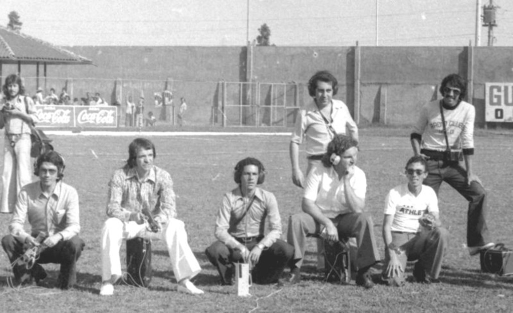 Time de jornalistas esportivos no gramado da Vila Capanema para um Atletiba em 1974, vitória atleticana por 2 a 0. Da esquerda para a direita: Gilberto Fontoura, Algaci Túlio, Nestor Baptista, Jota Agostinho, Augusto Mafuz (em pé), desconhecido e Édson Militão