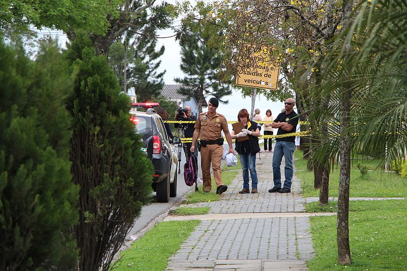 A polícia isolou o local onde a garota foi baleada. No detalhe, policial carrega mochila que seria da vítima | Átila Alberti/Tribuna do Paraná