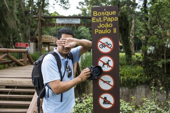 Fotógrafo faz sinal mostrando que não é permitido fotografar no bosque |