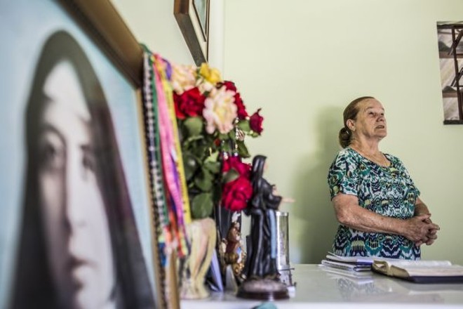 Dona Joana, ao lado do santuário que ostenta imagens de Santa Paulina e Santa Rita de Cássia | 