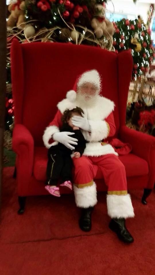 Foto postada em rede social mostra Papai Noel cobrindo rosto de criança no momento da foto | Reprodução/Facebook