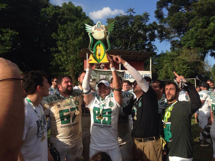 O wide receiver Adam Rodrigues ergue o troféu da Conferência Centro-Sul de futebol americano, conquistado pelo Coritiba Crocodiles | Dayane Wosch / Divulgação