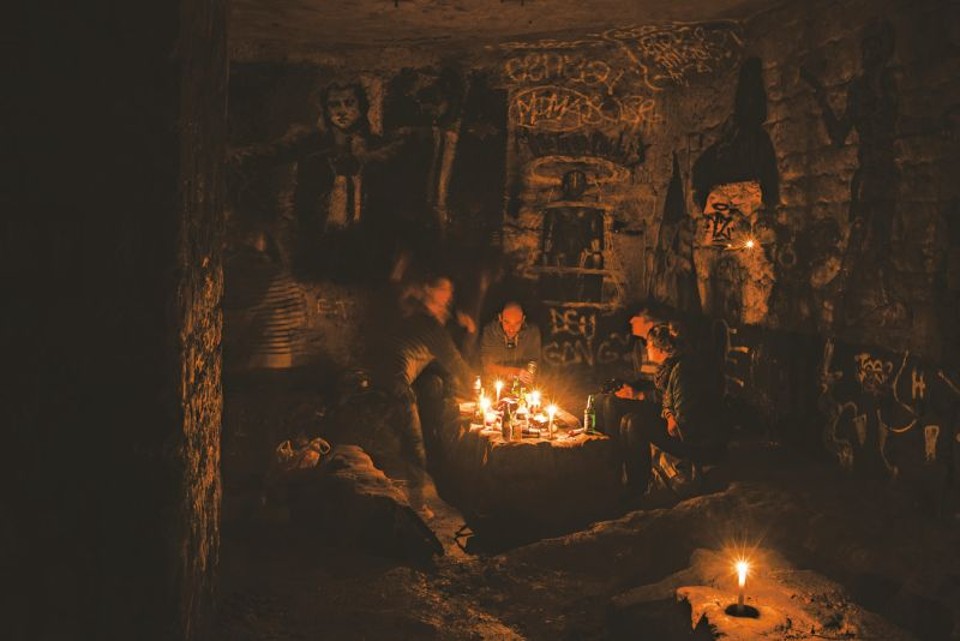 O artista conhecido como Nobad, no centro, acompanhado de amigos em uma galeria nas catacumbas de Paris. Frequentadores habituais tentam manter em segredo a entrada do túnel | Dmitry Kostyukov para The New York Times