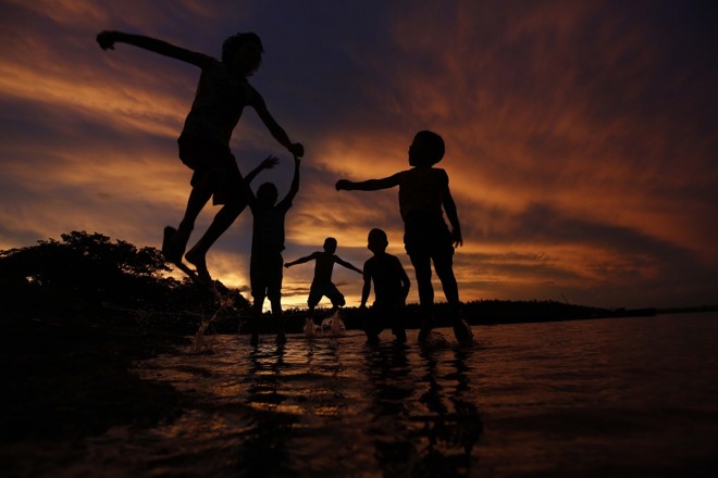 Águas da divisa. Crianças brincam ao pôr do sol entre Paraná e Mato Grosso do Sul, no Rio Paraná. | 