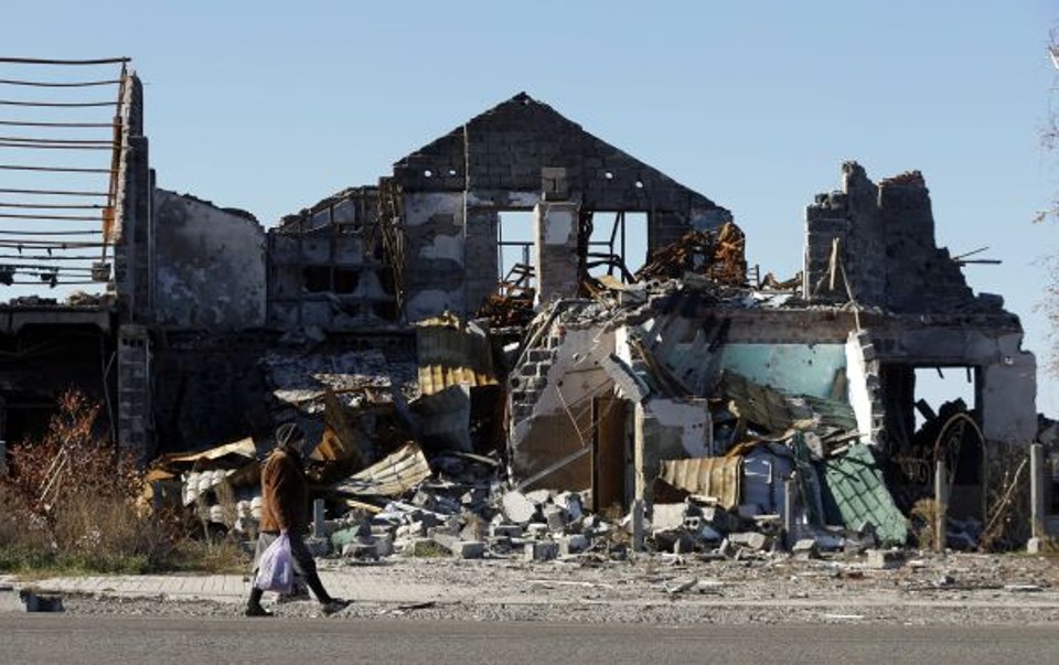 Mulher caminha perto de casas destruídas por bombardeios recentes na cidade de Slavyansk,  Ucrânia | REUTERS/Vasily Fedosenko