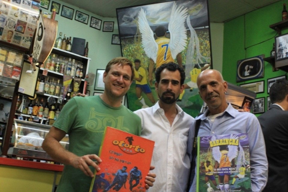 O artista Juliano Grus, Arlindo Ventura e o fotógrafo João Henrique Le Senechal com exemplares do livro sobre Garrincha que tem fotos do bar na capa e contracapa. A obra do francês Dominique Beaucant traz informações e imagens raras do craque, em 288 páginas e 245 fotos | Michel Prado