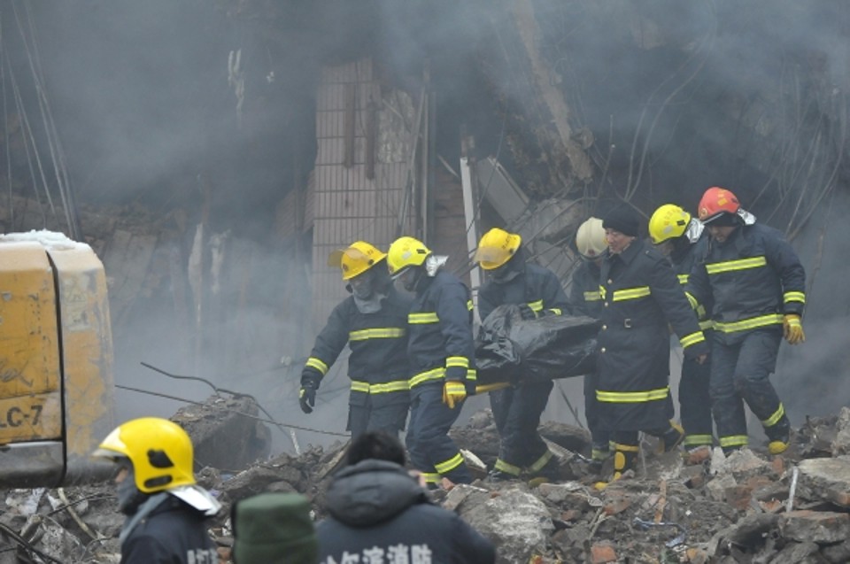 Bombeiros carregam o corpo de um companheiro, que foi enterrado depois de um prédio desabou durante um incêndio, em Harbin , província de Heilongjiang | REUTERS/Stringer