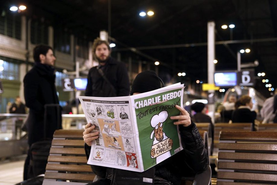 Pessoa lê a primeira edição do Charlie Hebdo após o atentado que matou jornalistas e chargistas | EFE/Yoan Valat