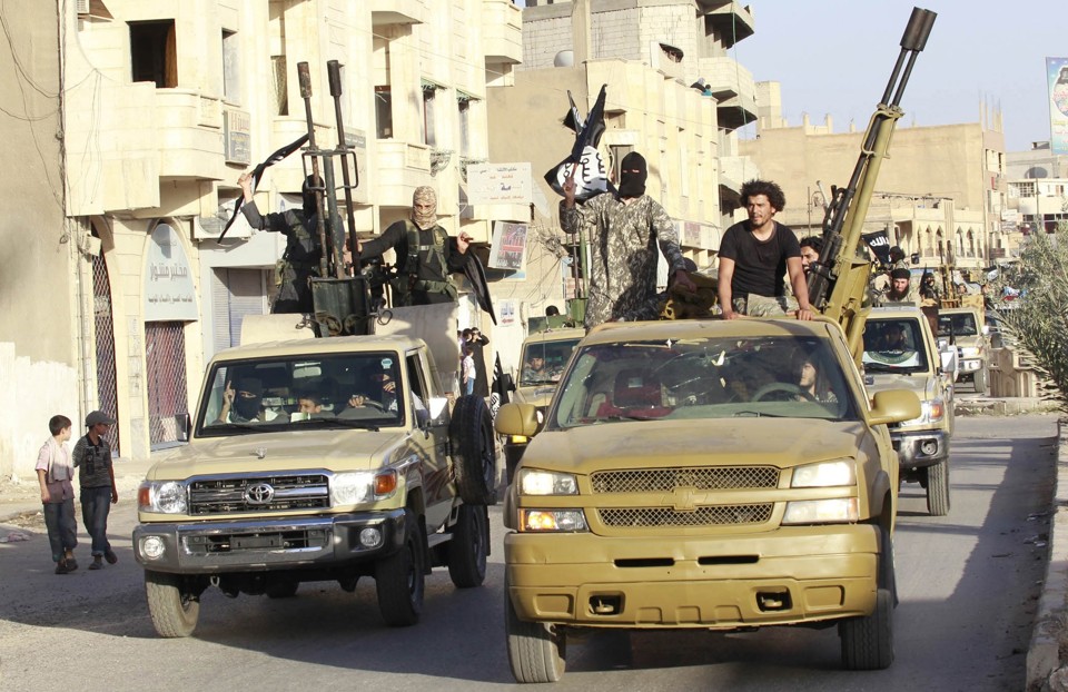 Em meio a veículos blindados e armamentos pesados, militantes do Estado Islâmico desfilam pelas ruas de Raqqa, na Síria, para celebrar a tomada de poder na região, em junho do ano passado | STRINGER