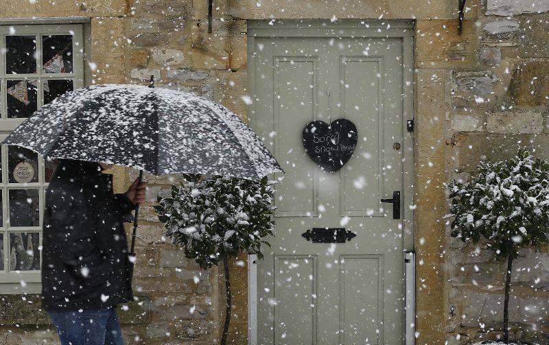 Pessoa passa em frente a loja fechada por causa da neve em Ashford, na Inglaterra | Darren Staples/Reuters