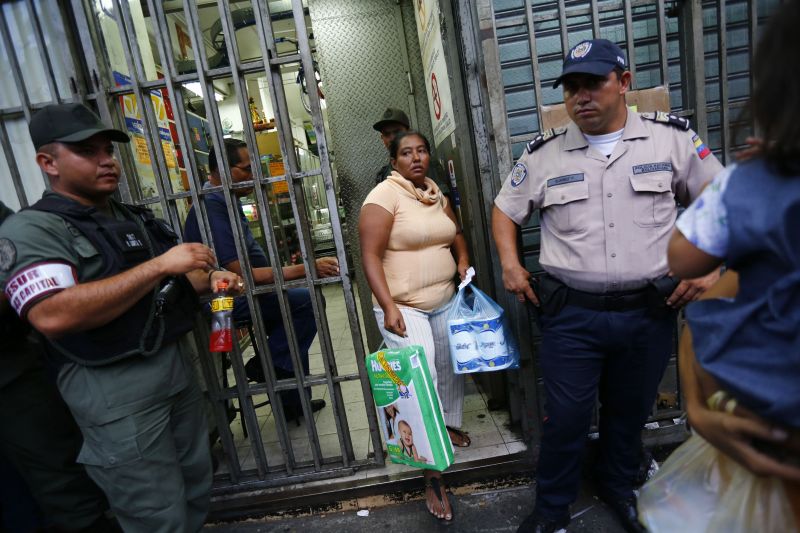 Policiais fazem a segurança em frente a um supermercado de Caracas | Jorge Silva/Reuters
