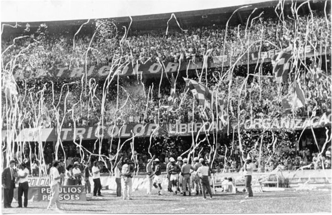 Bandeira, papel e foguete:Nos anos 90 a festa das torcidas rolava quase sem restrições  e o que é melhor, liberada para os adeptos dos dois times. Até mesmo baterias de fogos de artifício eram acionadas de dentro dos estádios, normalmente atrás dos gols, e ensurdeciam os presentes por longos minutos. Papel picado, cataratas de papel higiênico arremessado das arquibancadas, fumaça colorida disparada de extintores e bandeiras de todos os tamanhos e cores tremulando. Não consta que alguém tenha morrido por causa de festa de torcida. | 