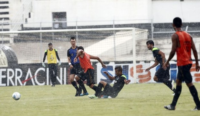 Jogadores disputam a bola em campo bastante molhado |