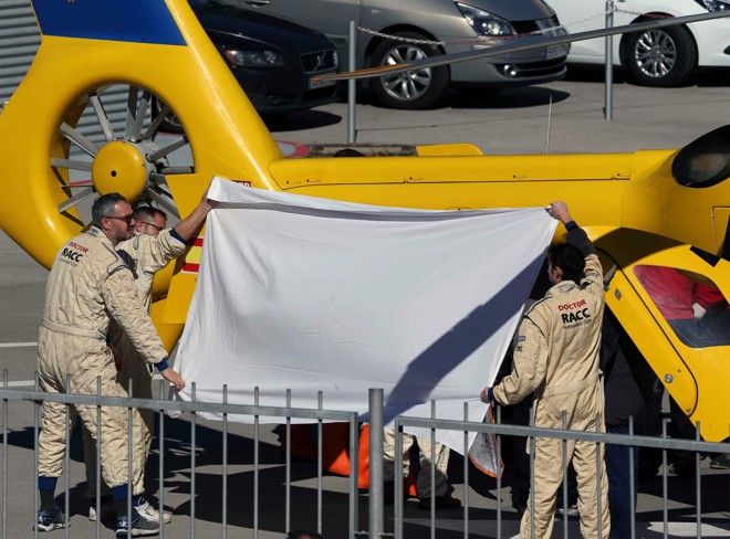 Equipe de apoio protege Fernando Alonso do sol, ao mesmo tempo que impede a visão do estado do piloto. | Toni Albir/ EFE