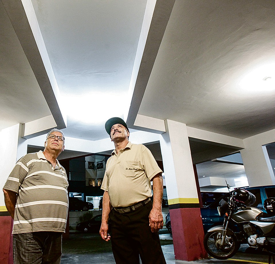 Síndico João Dias (esquerda) e o porteiro do condomínio Maria Tereza, na Vila Hauer: troca das lâmpadas da garagem para economizar na conta de luz. | Daniel Castellano/Gazeta do Povo