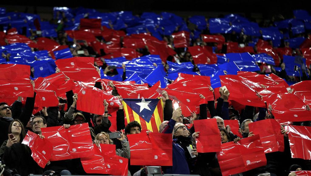 Durante a execução do hino do Barça, foram erguidos papéis brilhantes amarelos, azuis e grenás nas arquibancadas, formando o desenho da camisa 12 | Alberto Estévez/EFE