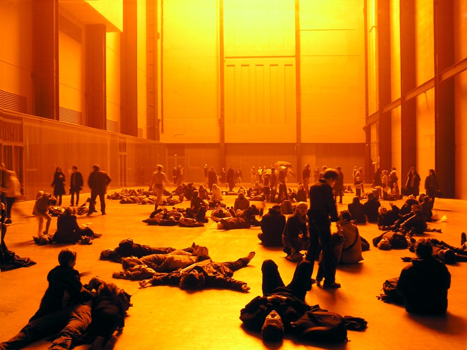 Pessoas iluminadas pelo sol falso de Eliasson em The Weather Project (2004), na Tate Modern. | Bjoss/Creative Commons