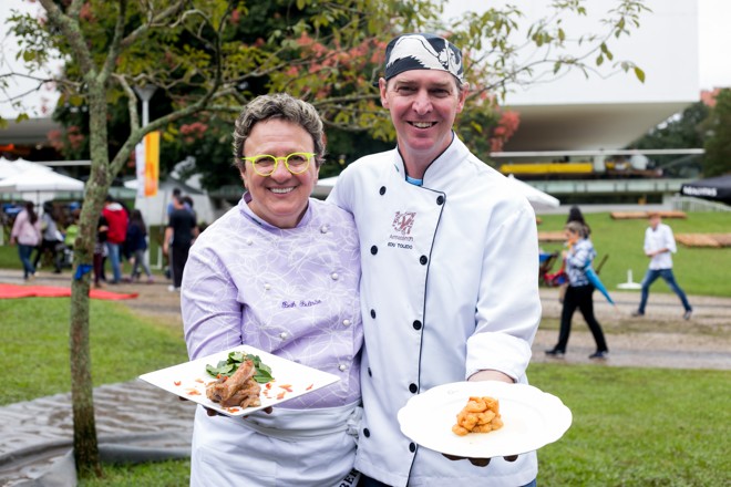 Os chefs Eduardo Toledo, do Armazém 71, de Curitiba, e Beth Beltrão, do Virada’s do Largo, de Tiradentes (MG), com seus pratos Camarão Crocante com molho de champagne e costelinha com mexerica com açúcar mineiro no Gastronomix | Annelize Tozetto
