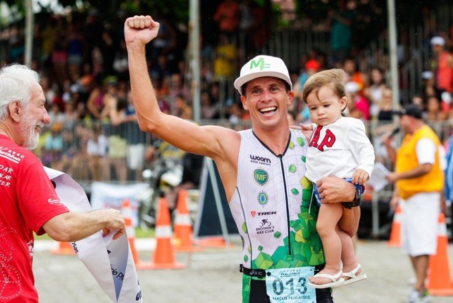 Marcus Vinicius Fernandes cruza a linha de chegada da prova da elite masculina com o filho Pedro no colo. | Daniel Castellano/Gazeta do Povo