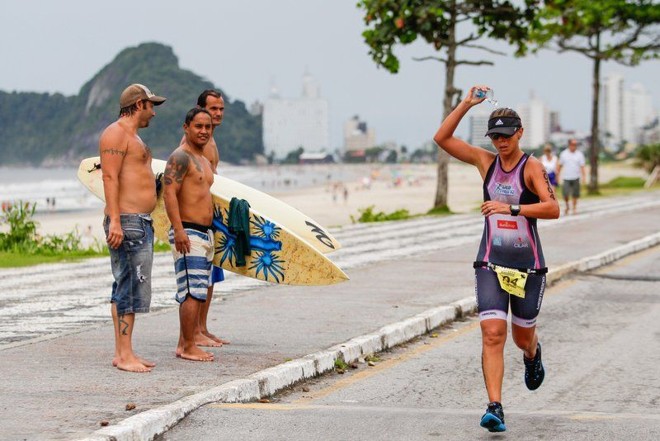 Competidora se refresca diante dos surfistas na Praia Brava de Caiobá. | Daniel Castellano/Gazeta do Povo
