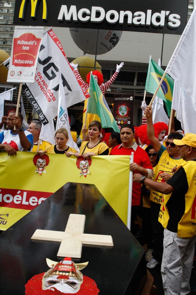 No saguão do Museu de Arte de São Paulo (MASP), cerca de 700 pessoas se reuniram com cartazes, muitas fantasiadas como o palhaço “Ronald McDonald”, e no final incendiaram um caixão simbolizando o enterro do personagem. | Carlos Villalba R./EFE