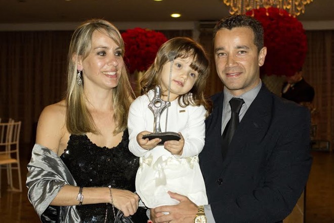 Em tempo de comemoração, o casal Isabelle Nara Juchen e Steve Carvalho Kos com a filha, Katherine, que exibe o prêmio Empresa de Destaque do Paraná 2014, concedido pelo SENAP à K 11 Produtora, empresa de Carvalho Kos, de foto e vídeo, operando ao lado da Casa do Convite. | Divulgação