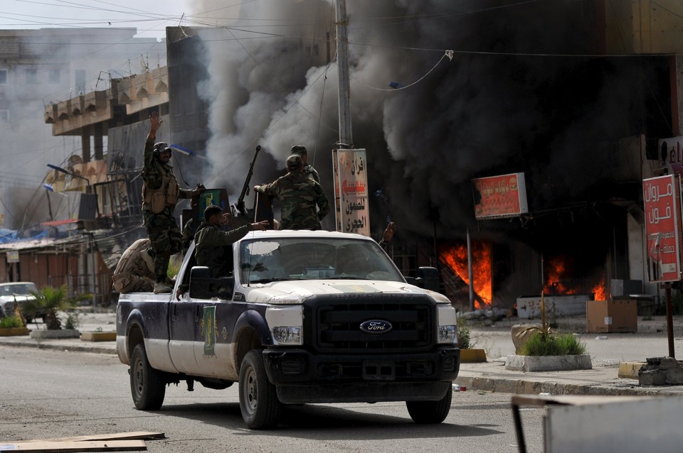 Políticos acusam membros de força de segurança e paramilitares por caos em Tikrit Membros das forças Hashid Shaabi passam por lojas incendiadas no bairro al-Qadisiya, ao norte de Tikrit | STRINGER/REUTERS