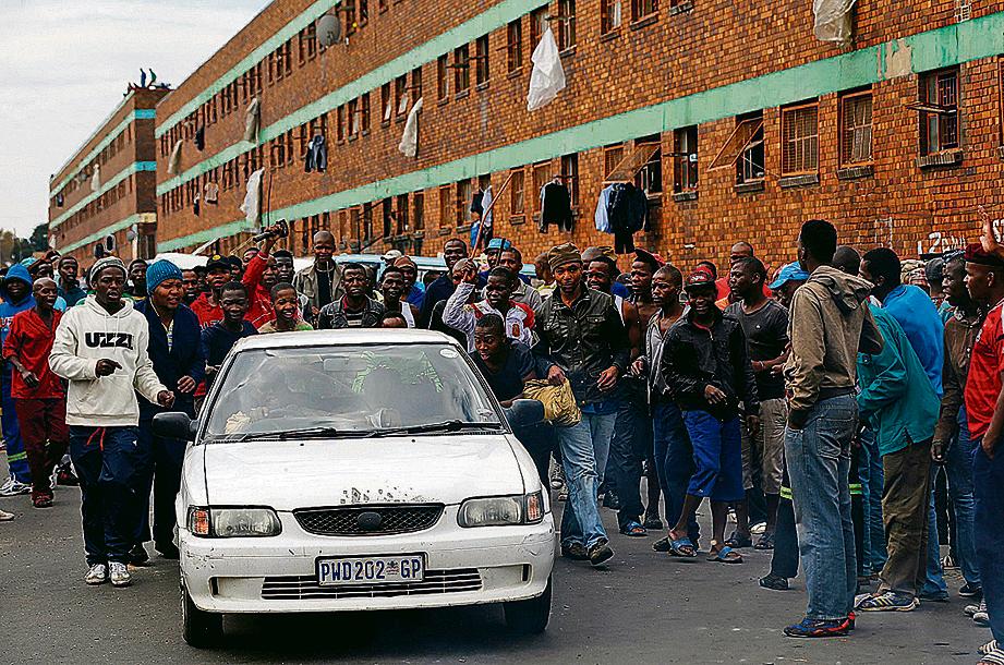 Grupo cerca carro de imigrante na cidade de Johannesburgo, onde veículos e lojas foram incendiados. | Siphiwe Sibeko / Reuters